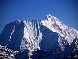 Kathmandu Mountain Flight 05-1 Menlungtse The dramatic south face of Menlungtse (7181m) shines in the early morning sun on the Kathmandu mountain flight. Menlungtse has a long summit ridge from the lower west summit (7023m) on the left to the higher east summit (7181m) on the right. Menlungtse has only been climbed a few times because of its extremely difficult steep faces. The Menlung La pass from Nepal into Tibet is on the lower right.